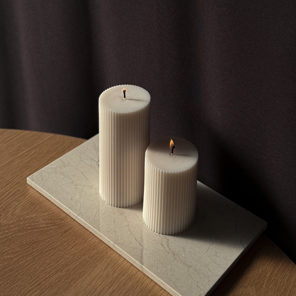 ROMI Kerze, minimalistisches Design, moderne Beleuchtung, skandinavischer Stil, gerippte Kerze, elegantes Wohnaccessoire, dezent stilvoll, Atmosphäre schaffen, sanfte Beleuchtung, zurückhaltende Eleganz.
