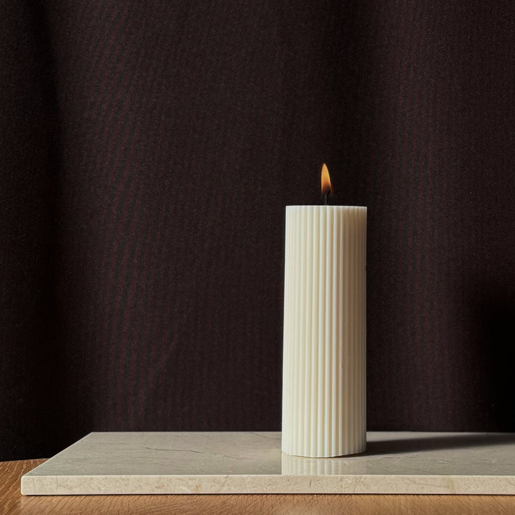 RUNA Kerze, minimalistisches Design, moderne Beleuchtung, skandinavischer Stil, gerippte Kerze, elegantes Wohnaccessoire, dezent stilvoll, Atmosphäre schaffen, sanfte Beleuchtung, zurückhaltende Eleganz.
